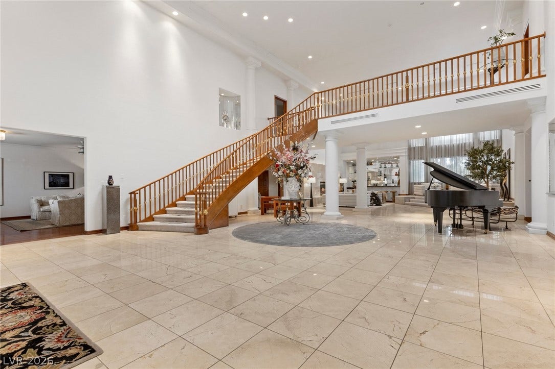 Polished stone tile floors and a soaring staircase define this grand foyer.