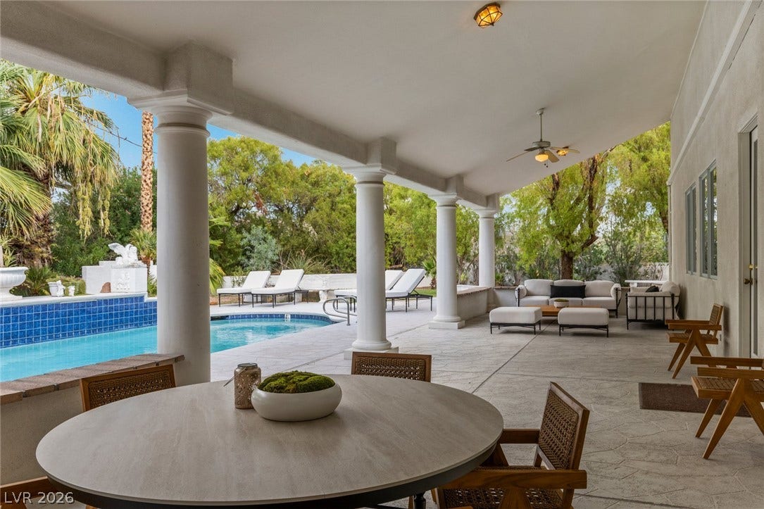 Classical columns frame a sheltered outdoor dining area overlooking the refreshing pool.
