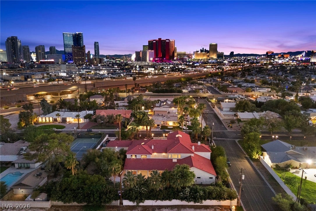 A sweeping panorama captures the illuminated city skyline beyond this residential neighborhood.