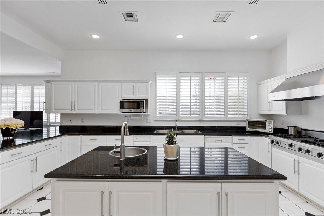 High ceilings and plantation shutters frame a modern kitchen with a spacious prep island.