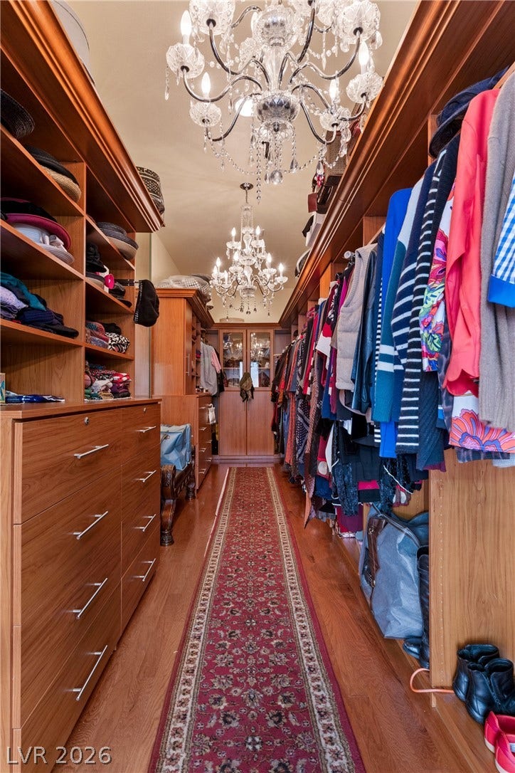 Gleaming wood floors and custom built-in cabinetry define this long walk-in closet.