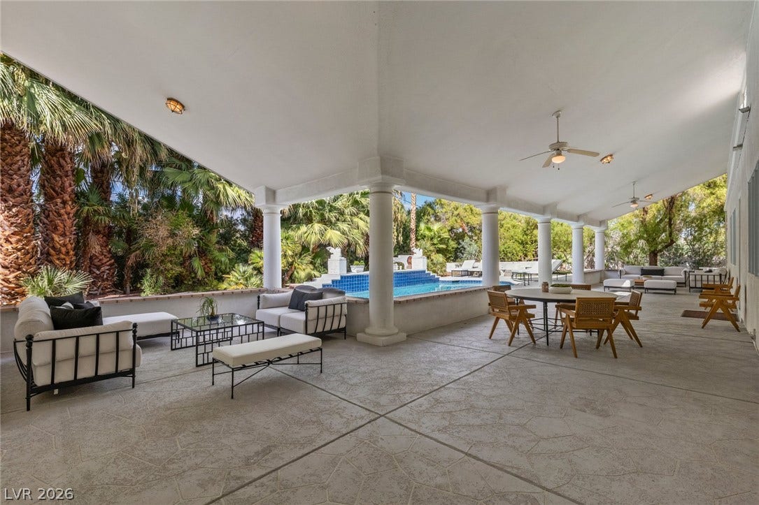 An expansive covered patio overlooks the sparkling pool and lush, tropical landscaped grounds.