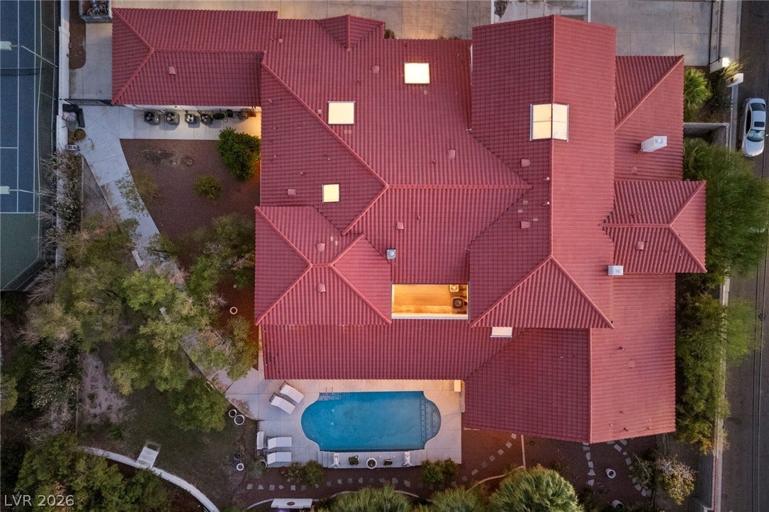 An aerial view showcases the intricate tile roof, skylights, and backyard swimming pool.