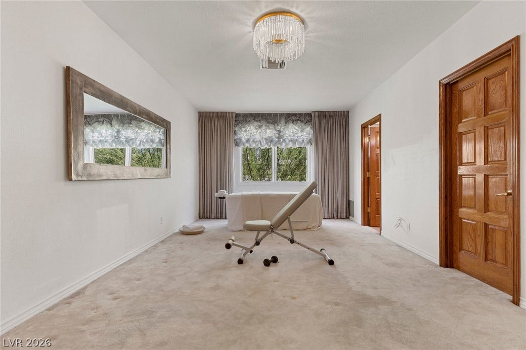 The upstairs bedroom, staged as a wellness room features plush neutral carpeting and rich wood doorways.