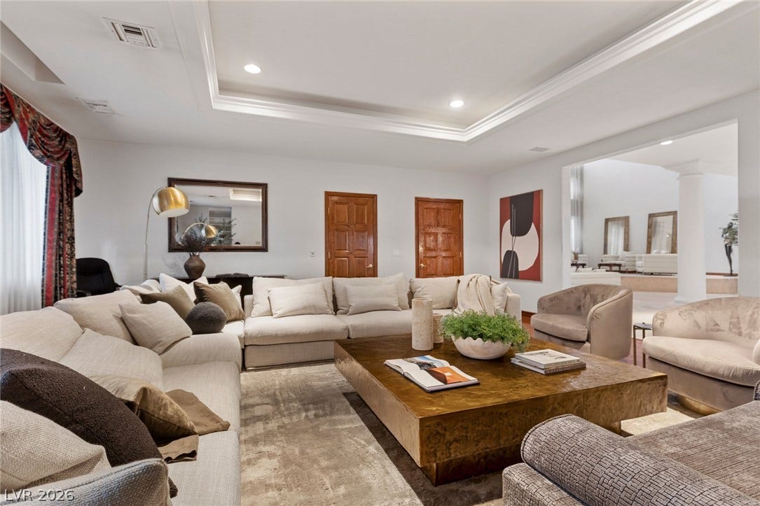 An elegant tray ceiling with crown molding defines this spacious formal living area.