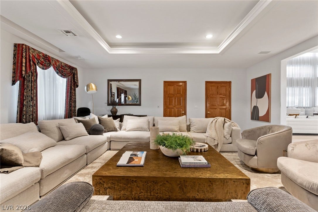 An elegant tray ceiling and recessed lighting crown this expansive, welcoming living room space.