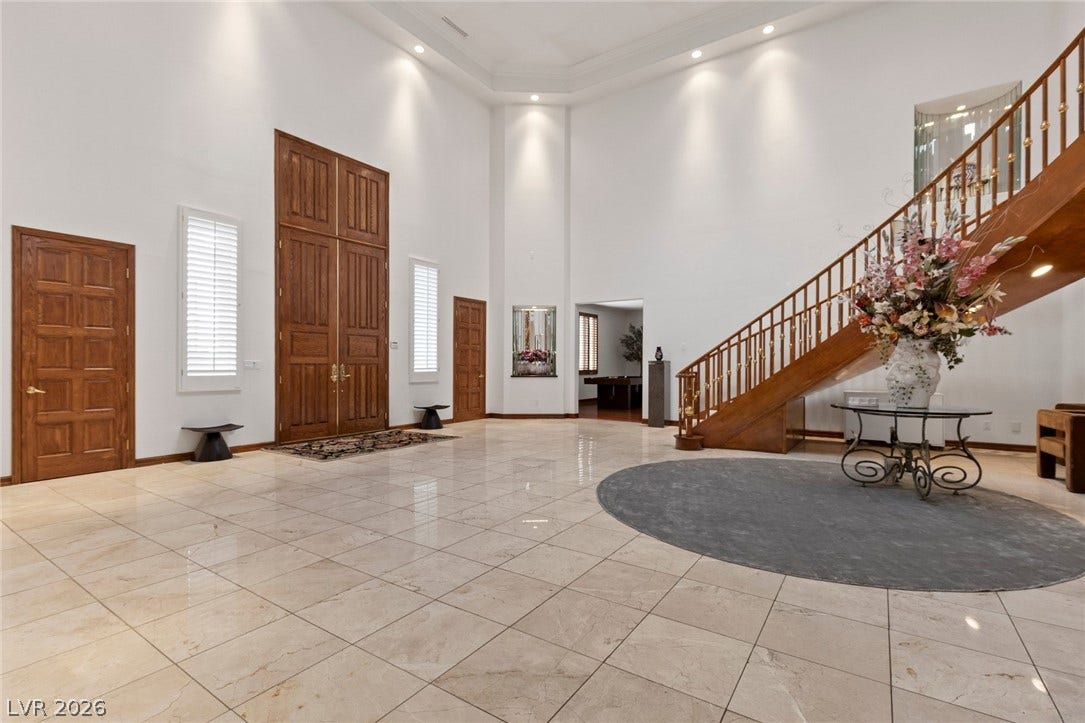 Polished stone floors and a curved wooden staircase define this soaring double-height entryway.