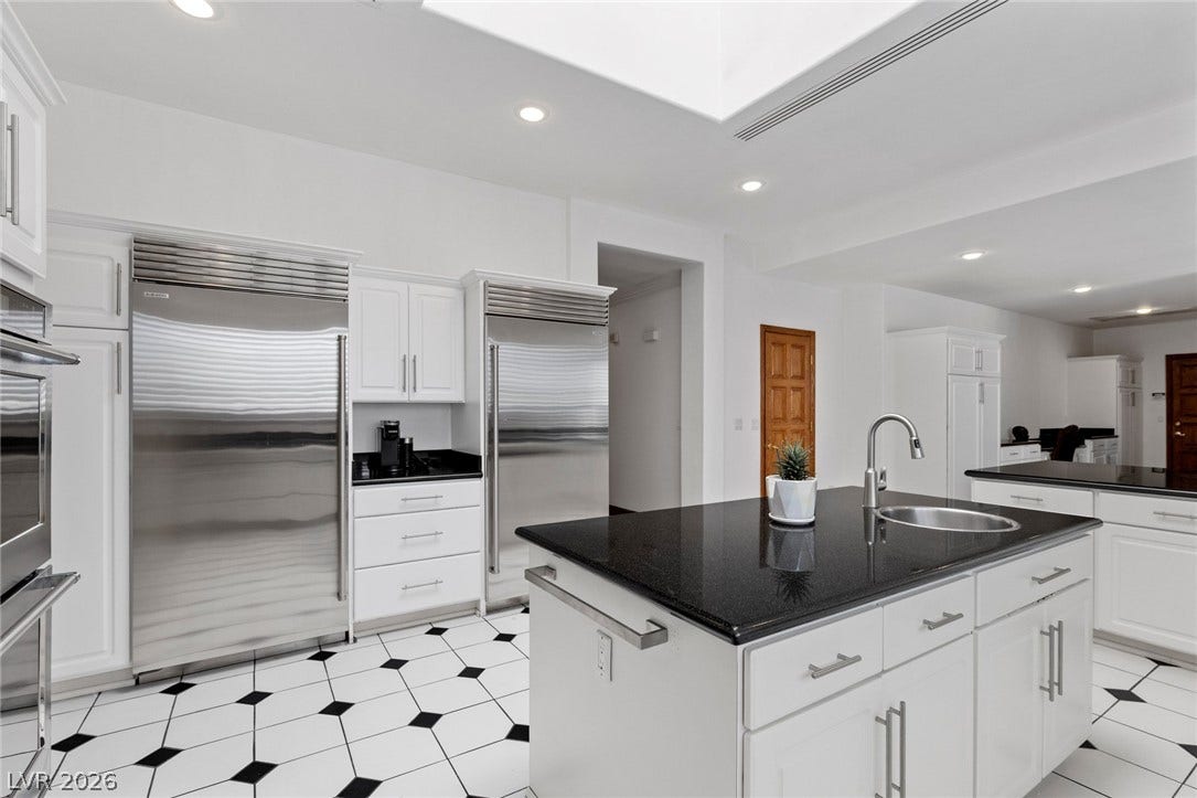 Polished granite countertops complement contrasting tile flooring under a bright skylight.