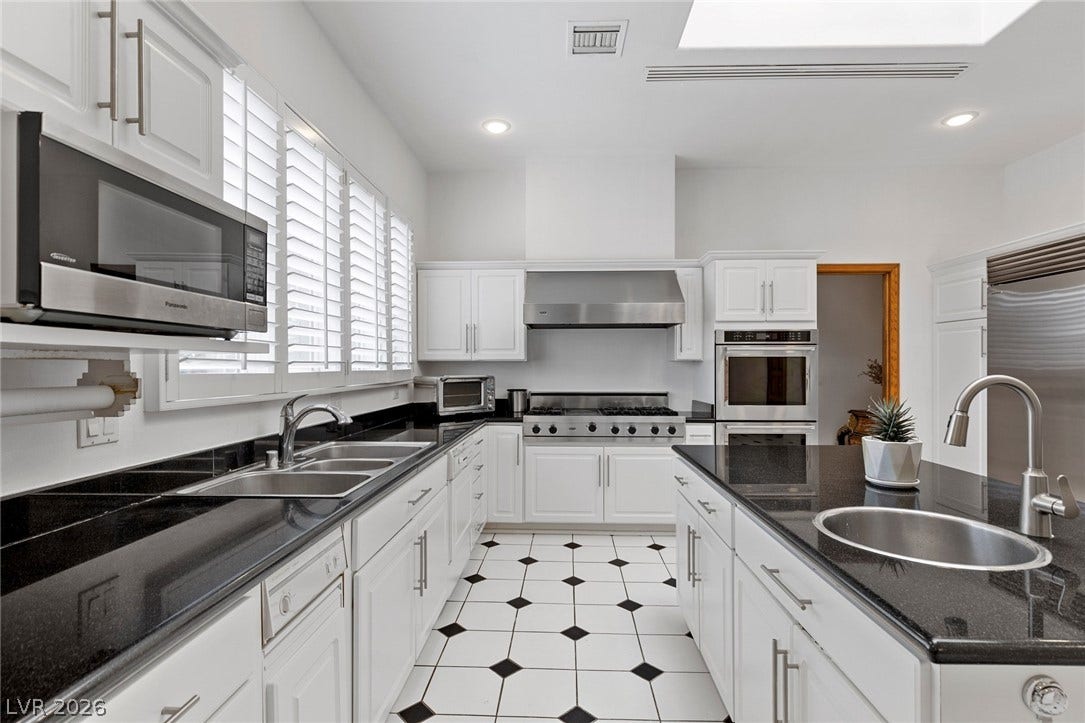 Granite countertops and clean white cabinetry frame this light-filled gourmet kitchen space.