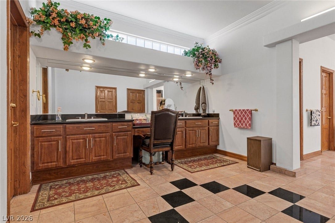 Ornate tiled floors, recessed lighting, and crown molding define this expansive double vanity bathroom.