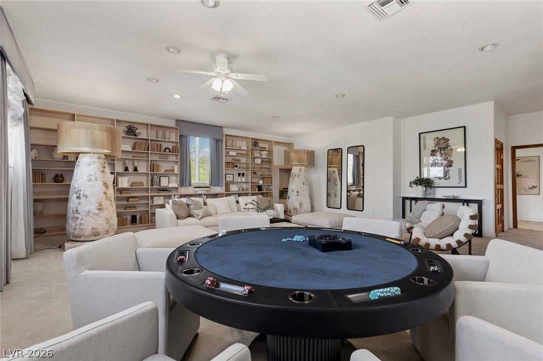 A spacious man cave above the primary bedroom with a secret staircase displays built-in shelving and expansive open floorplan layout.