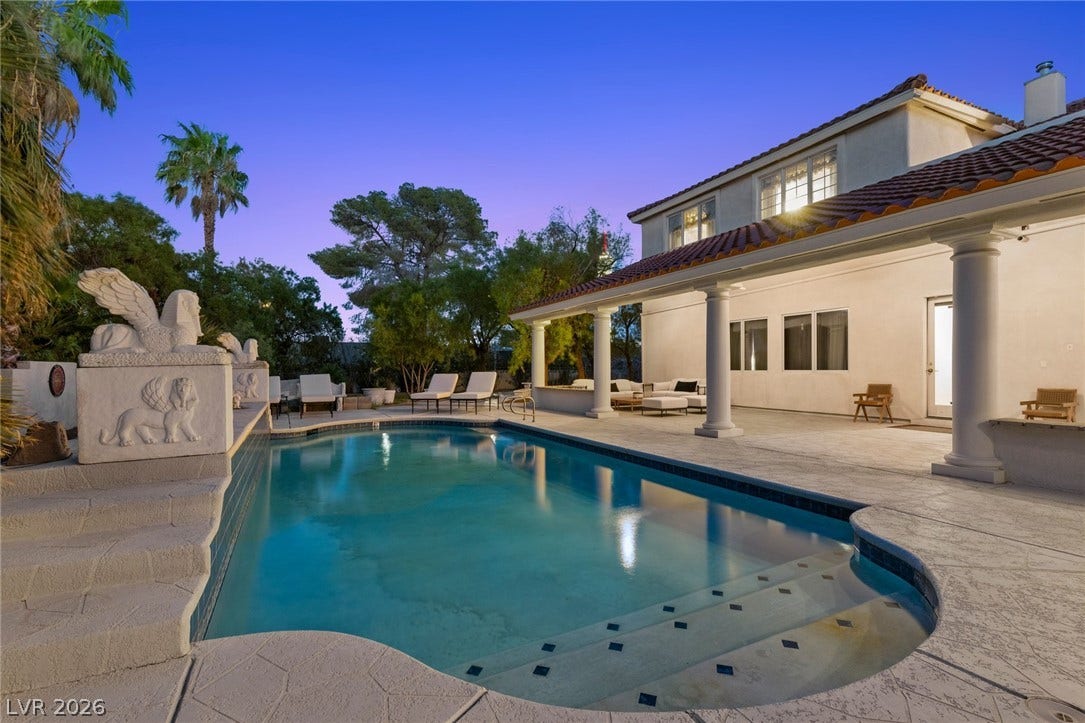 An inviting backyard pool area is bordered by a spacious covered patio and classic stucco architecture.