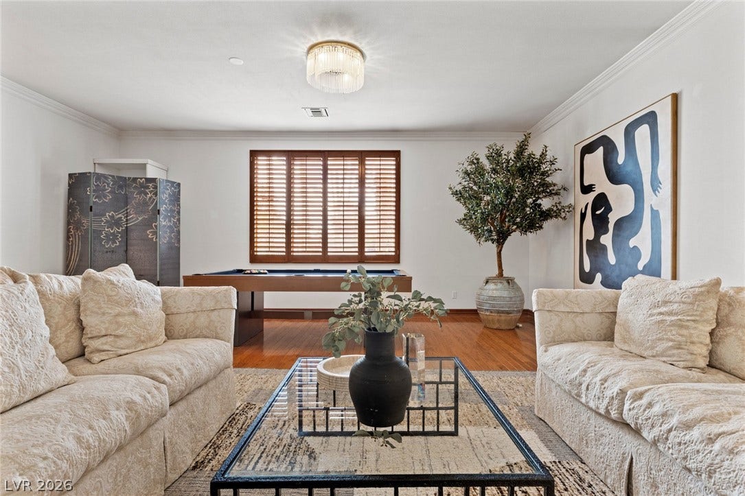 Gleaming hardwood floors and classic crown molding elevate this versatile recreation space.