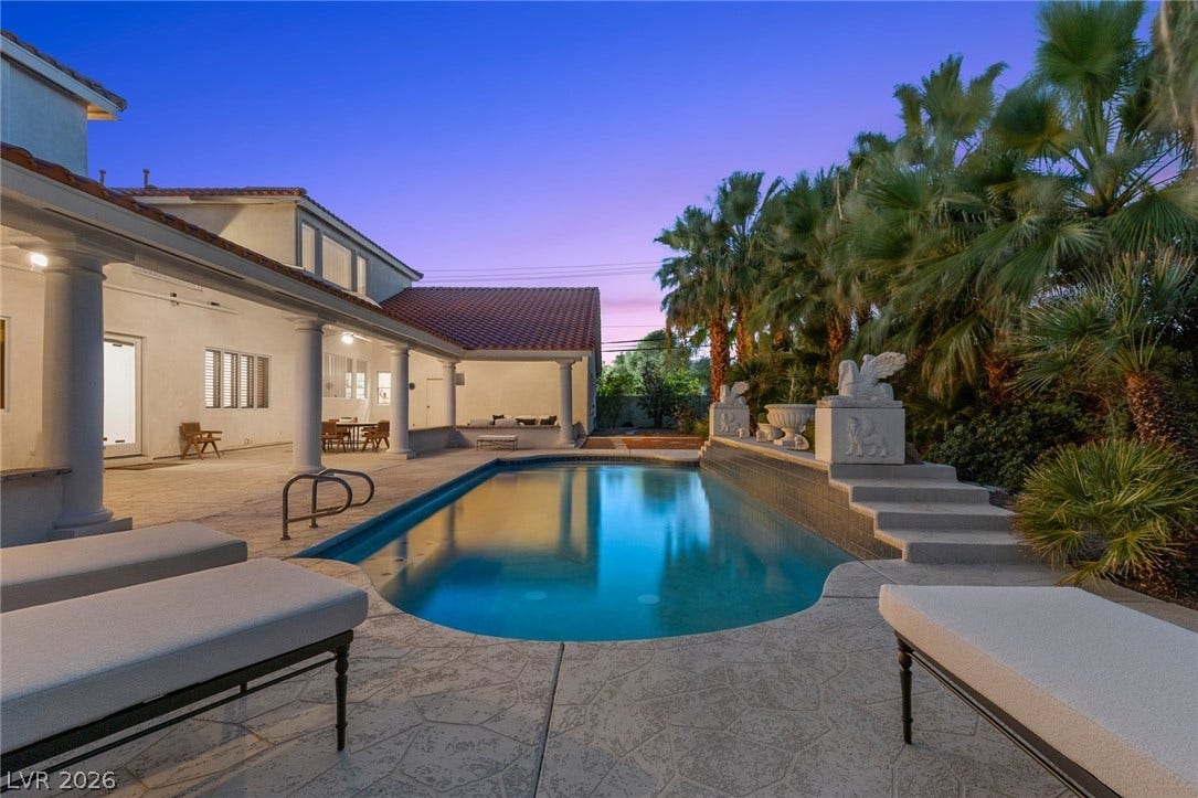 An inviting swimming pool anchors this private backyard terrace under a twilight sky.