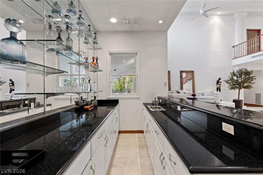 Polished granite counters and custom glass shelving define this stylish wet bar area.