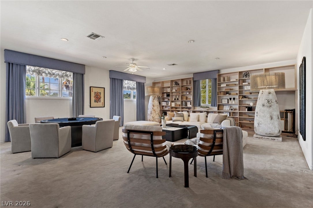 Recessed lighting and custom built-in shelving highlight this spacious carpeted living space.