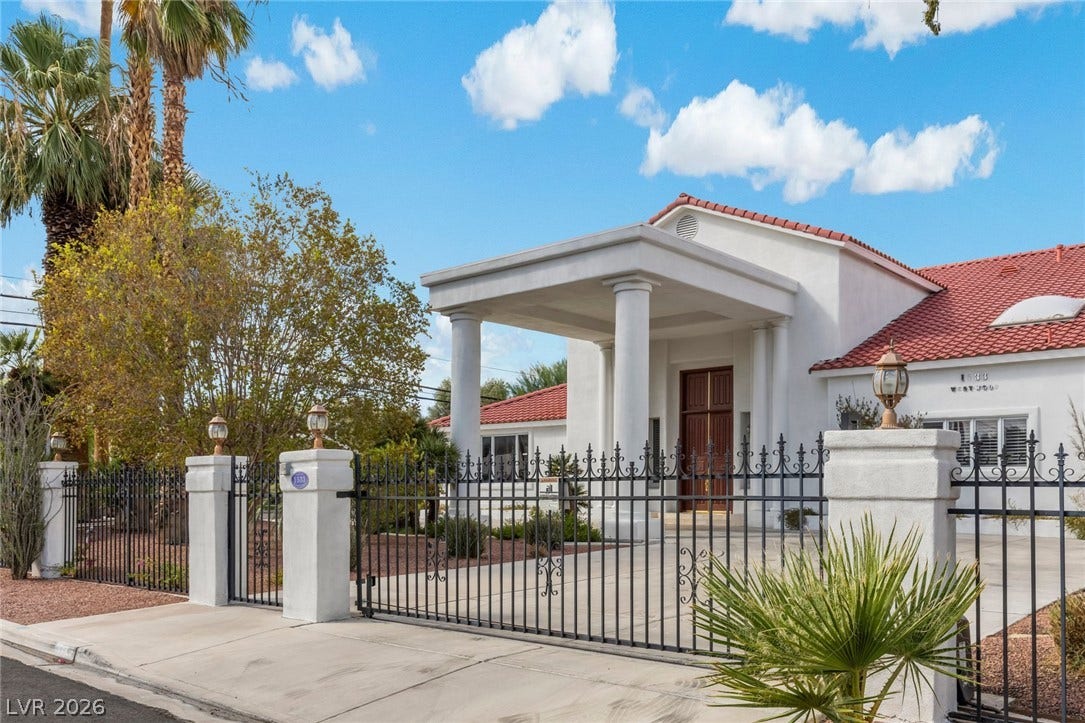 Stately pillars and a gated entrance define this striking Mediterranean-style estate.