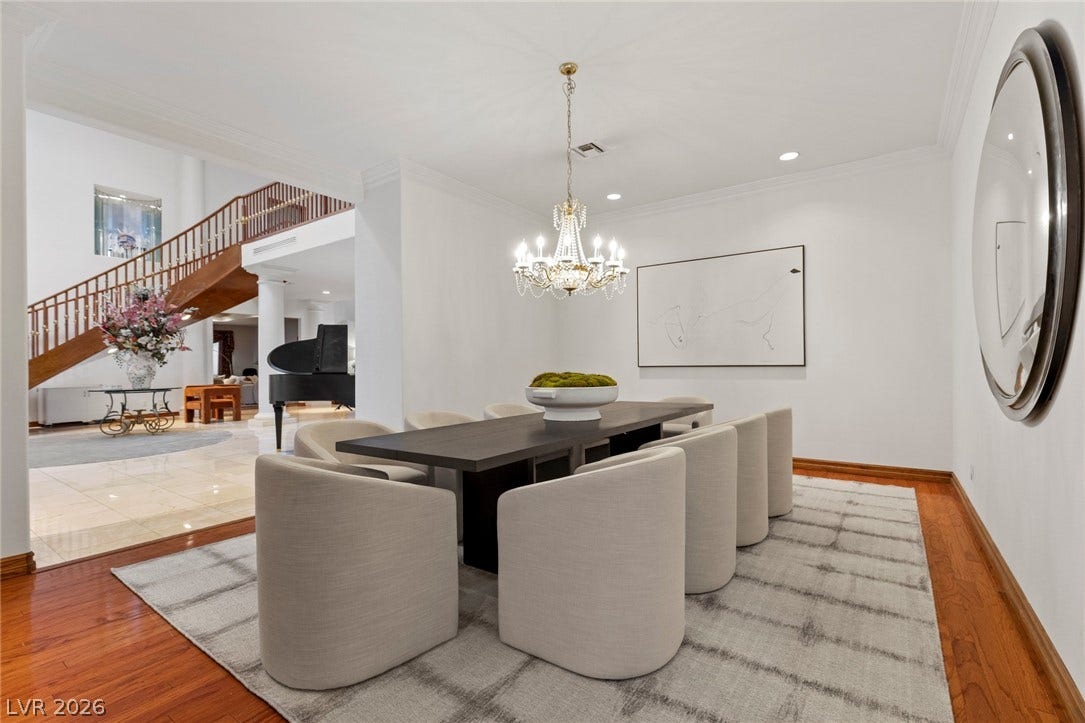 Gleaming hardwood floors and an elegant crystal chandelier elevate this spacious dining room design.