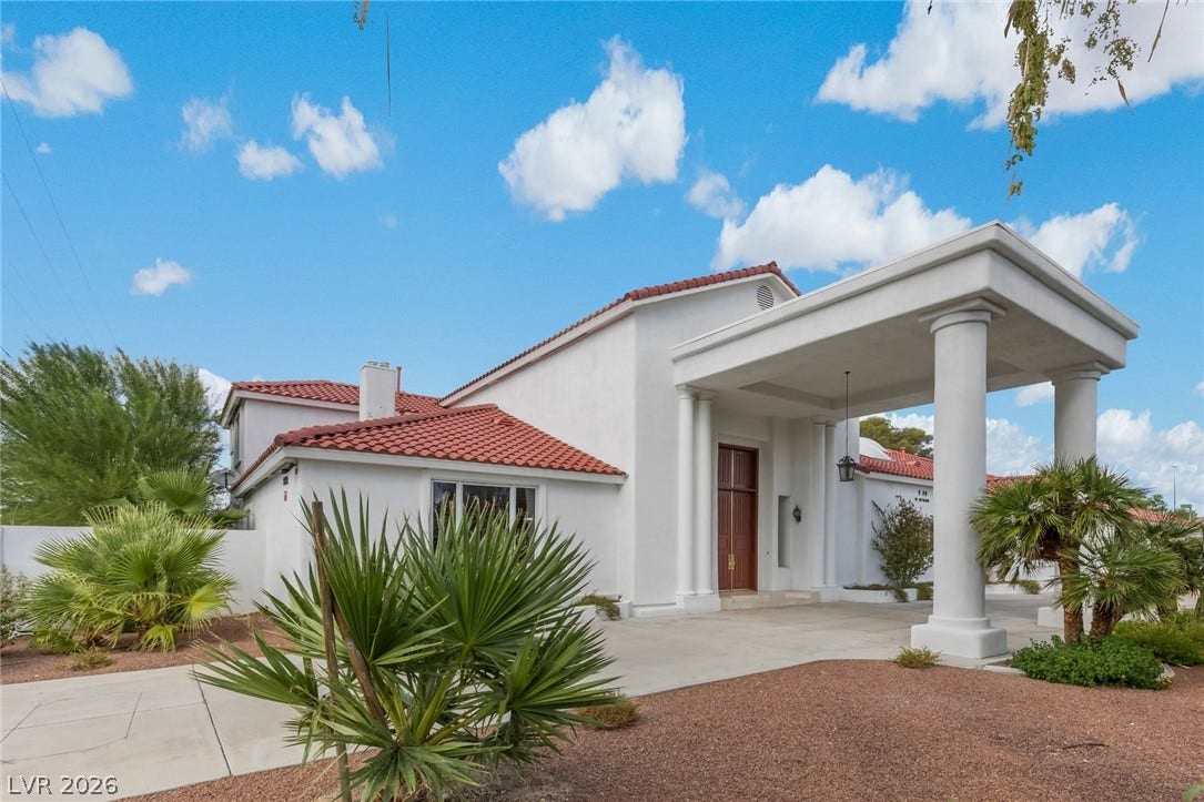 An elegant portico columns the entrance of this Spanish tile roofed estate.