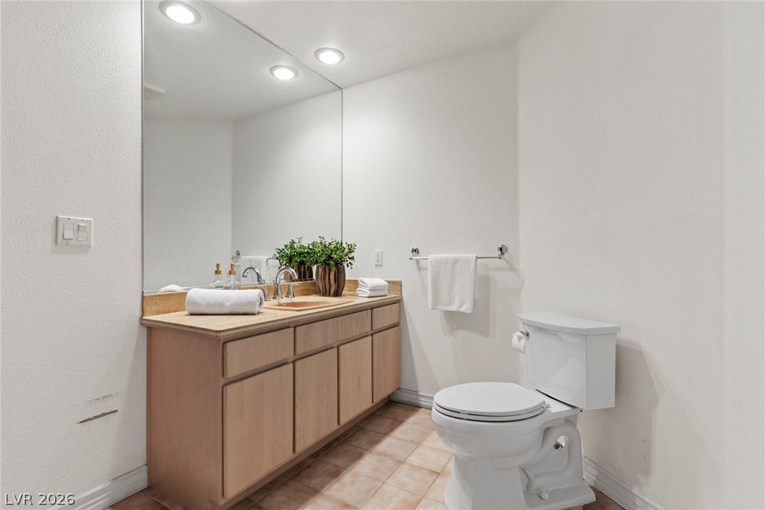 An expansive wall mirror and recessed lighting enhance this functional bathroom space.