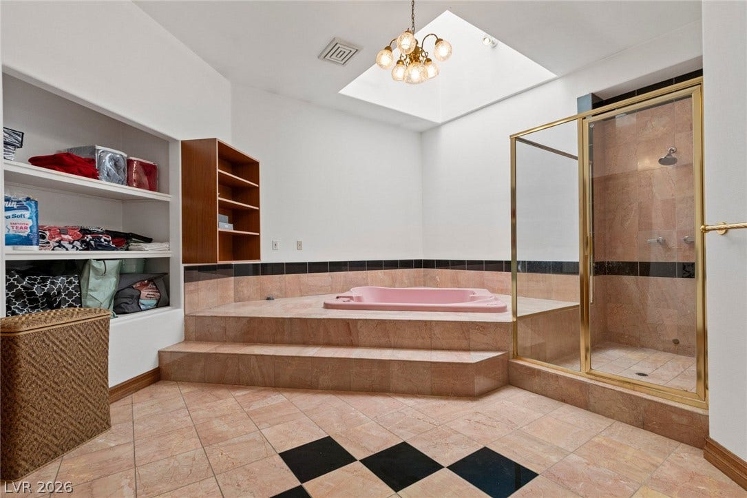 A spacious bathroom features tiled flooring, a glass-enclosed shower, and a built-in step-up soaking tub.