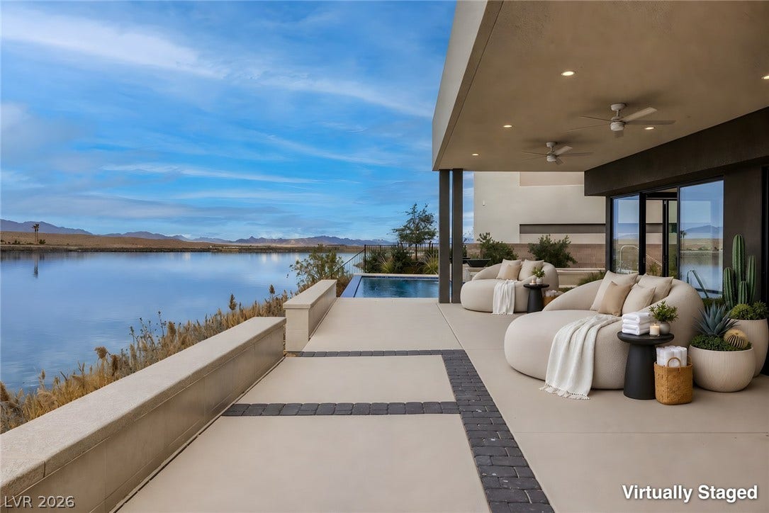 An covered patio overlooks peaceful water views alongside a private pool.