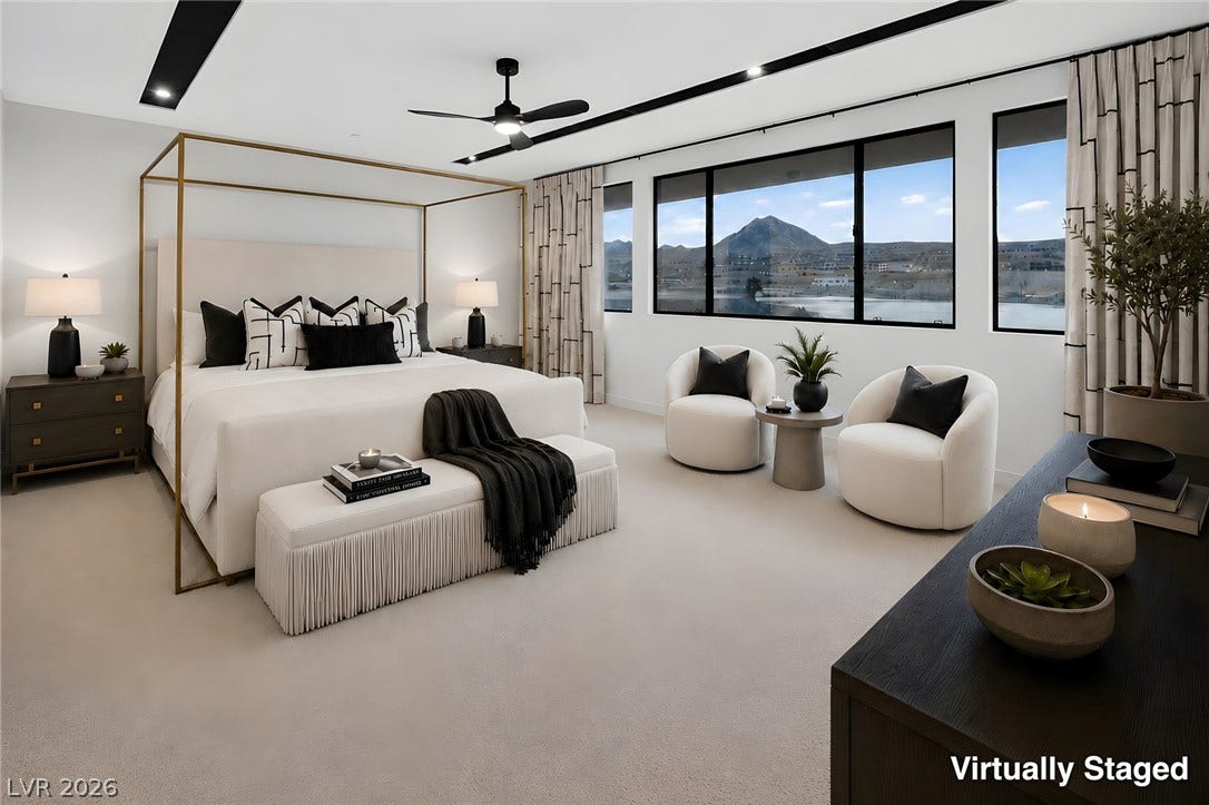 Large windows frame picturesque mountain and water views in this modern primary suite.