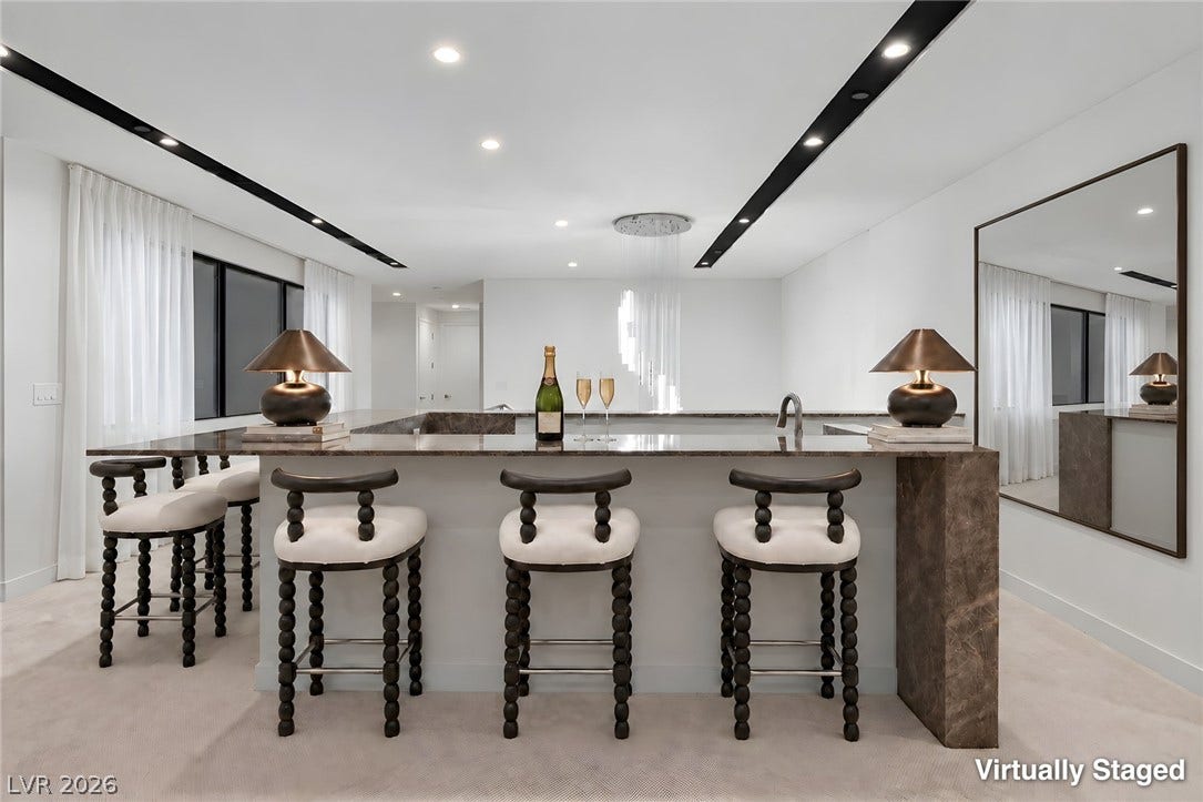 An elegant home bar features natural stone counters and recessed ceiling lighting.