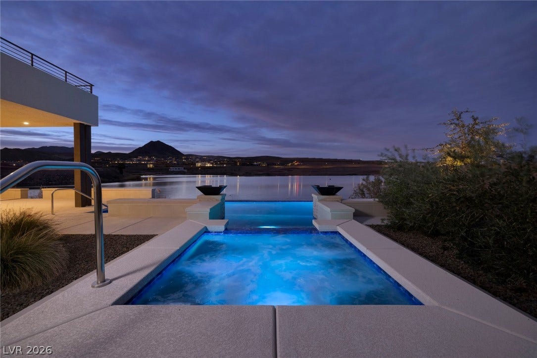 An elevated spa overlooks the serene lake waters and distant mountain peaks at twilight.
