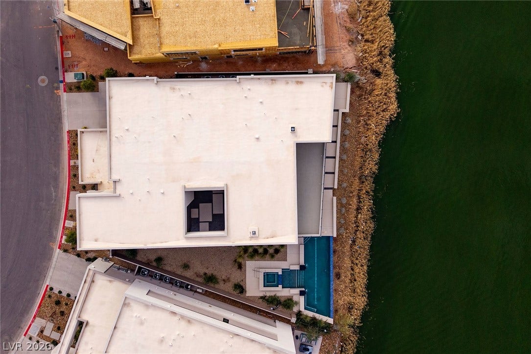 An aerial perspective showcases the waterfront setting and custom pool design.