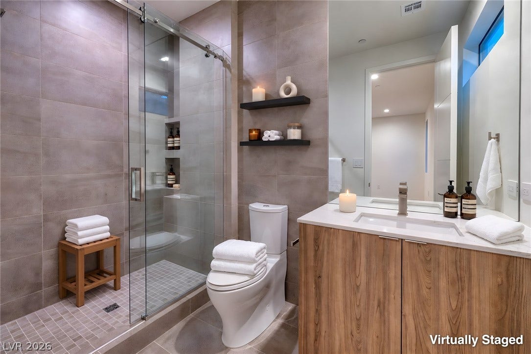 A glass-enclosed walk-in shower highlights this modern bathroom with a wood-front vanity.