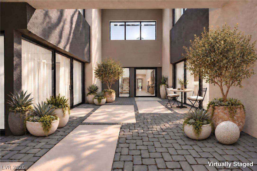 An inviting courtyard features modern stone pavers and sleek architectural details under an open sky.