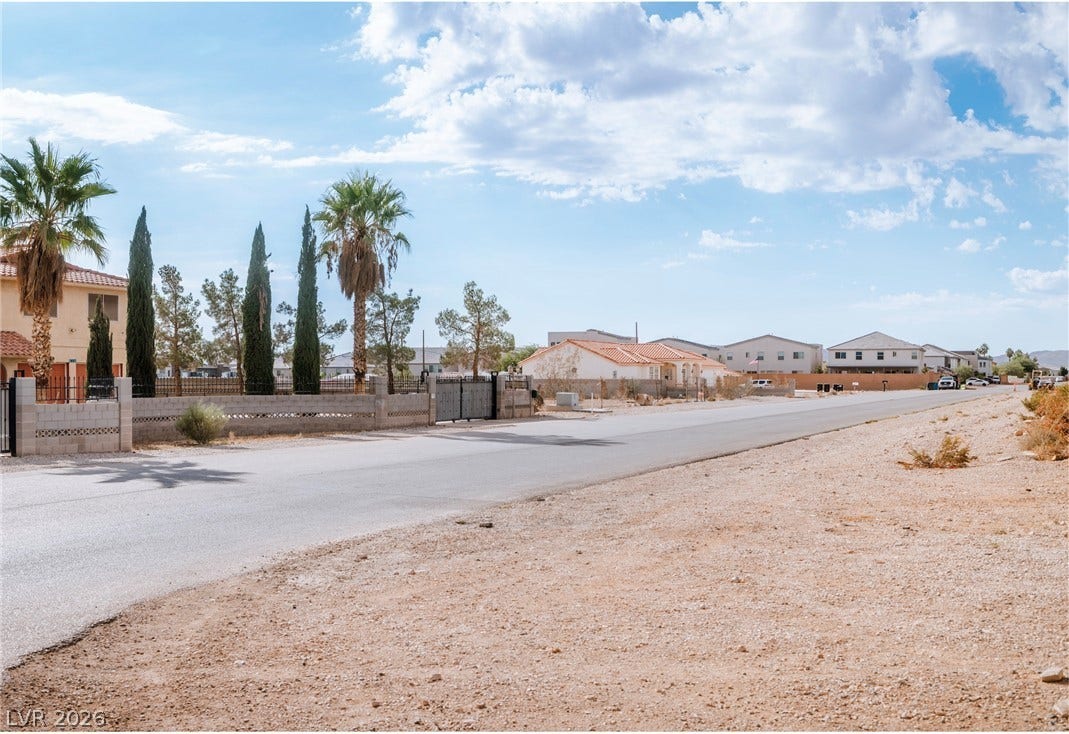 Redwood Street, Las Vegas, NV 89139 A paved residential street winds through a sunny desert neighborhood lined with palm trees.