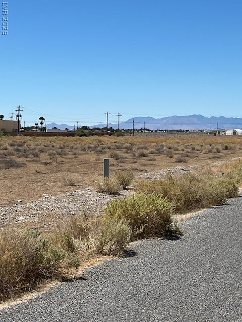 801 S Ford Loop, Pahrump, NV 89048 Distant mountains frame this open desert acreage bordering a paved roadway under clear blue skies.