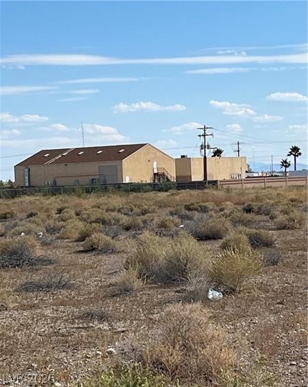 801 S Ford Loop, Pahrump, NV 89048 A spacious desert lot borders commercial properties under a bright blue sky.
