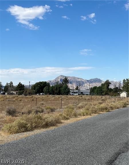 801 S Ford Loop, Pahrump, NV 89048 Dramatic mountain peaks rise in the distance beyond a fenced rural pasture under blue skies.