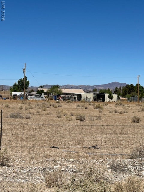 801 S Ford Loop, Pahrump, NV 89048 Rugged terrain and functional outbuildings sit under a vast blue sky with distant mountain views.