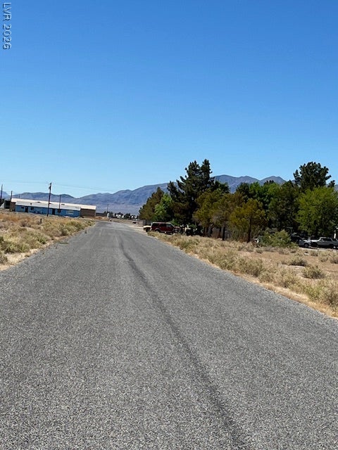 801 S Ford Loop, Pahrump, NV 89048 A paved roadway runs alongside mature trees beneath clear blue skies and distant mountain peaks.