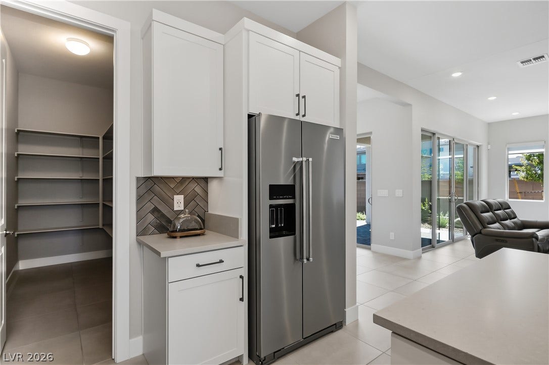 11164 Twisty Ridge Street, Las Vegas, NV 89183 Gleaming stone countertops and modern cabinetry frame the walk-in pantry in this open-concept kitchen.