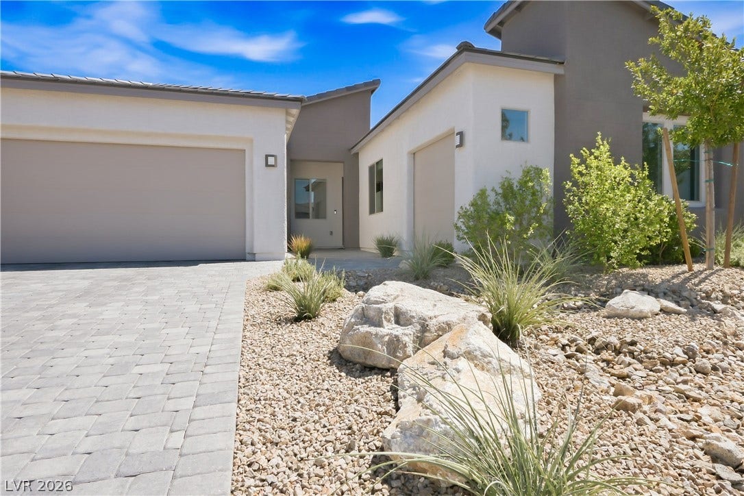 11164 Twisty Ridge Street, Las Vegas, NV 89183 A paved driveway leads to this modern stucco exterior featuring desert landscaping and clean architectural lines.