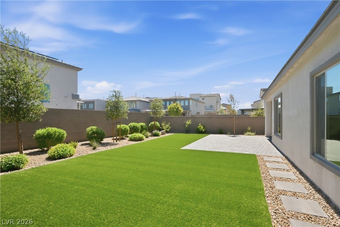 11164 Twisty Ridge Street, Las Vegas, NV 89183 A manicured lawn and stone pavers enhance this modern, private backyard setting.