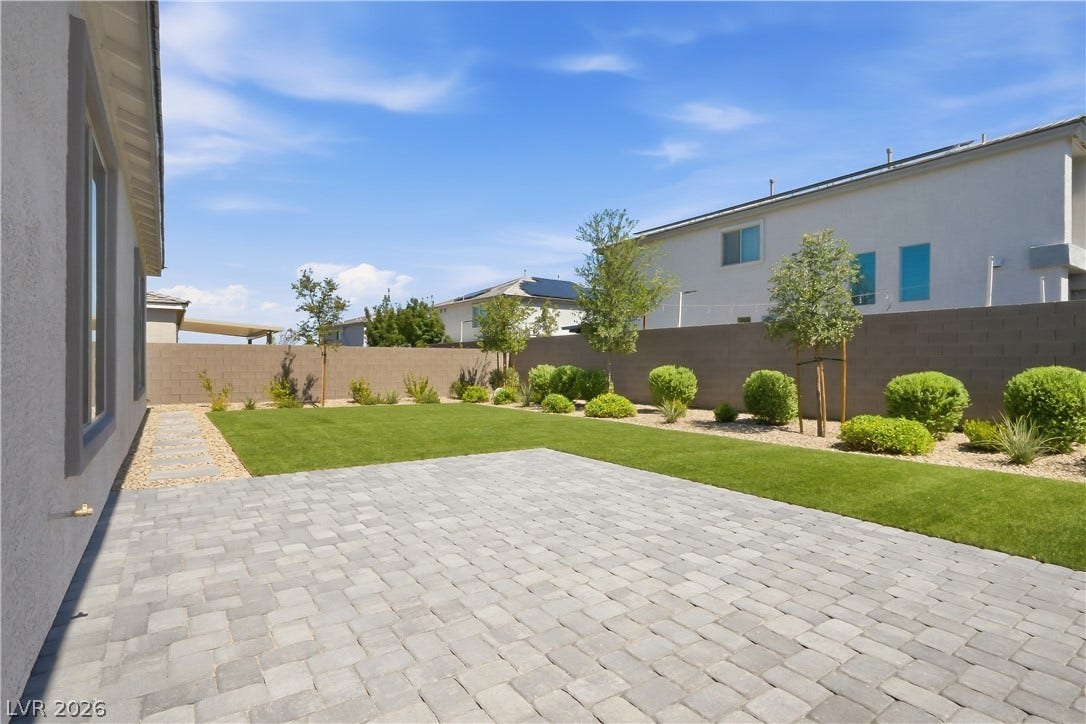 11164 Twisty Ridge Street, Las Vegas, NV 89183 An expansive paved patio overlooks a neatly manicured lawn enclosed by privacy fencing.