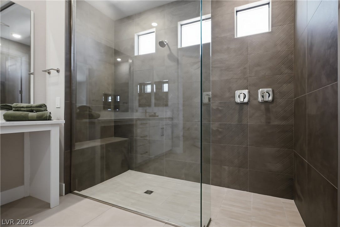 11164 Twisty Ridge Street, Las Vegas, NV 89183 A glass-enclosed walk-in shower features textured gray wall tile and a built-in bench.