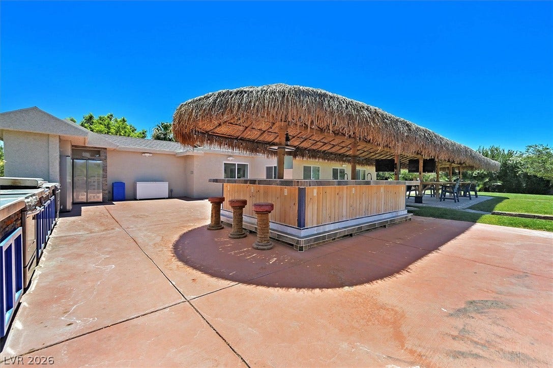 An inviting outdoor bar with a thatched roof creates a perfect entertainment spot.