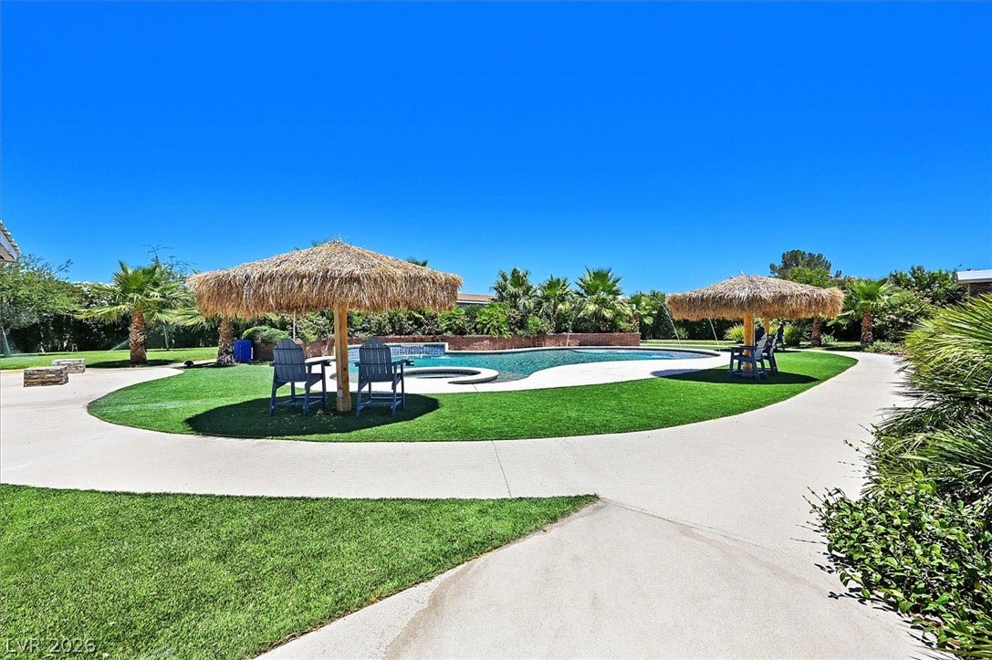 A private outdoor oasis features a refreshing pool, ample green space, and charming tiki umbrellas.