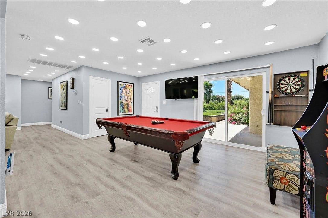 Recessed lighting illuminates this recreation room with hard flooring and convenient outdoor access.