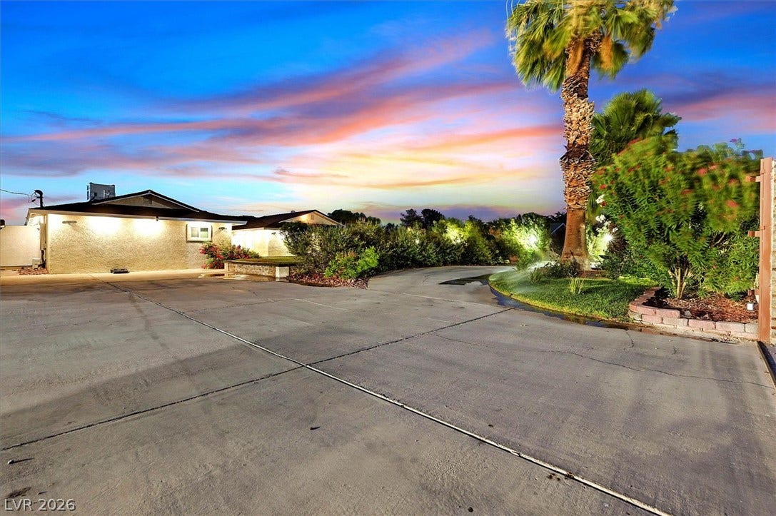 A graceful driveway leads to a property surrounded by lush, well-maintained landscaping.