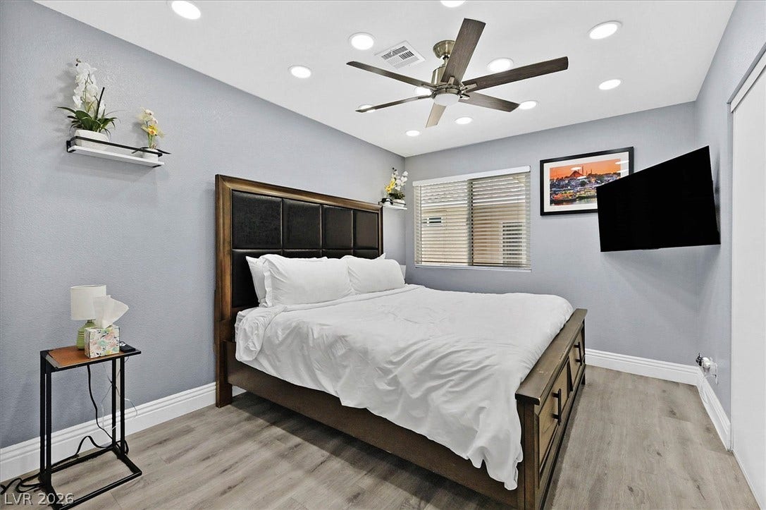 An inviting bedroom features recessed lighting, a modern ceiling fan, and durable wood flooring.