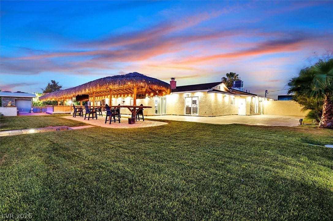 An inviting backyard oasis offers a covered patio with bar seating, ideal for entertaining under the evening sky.