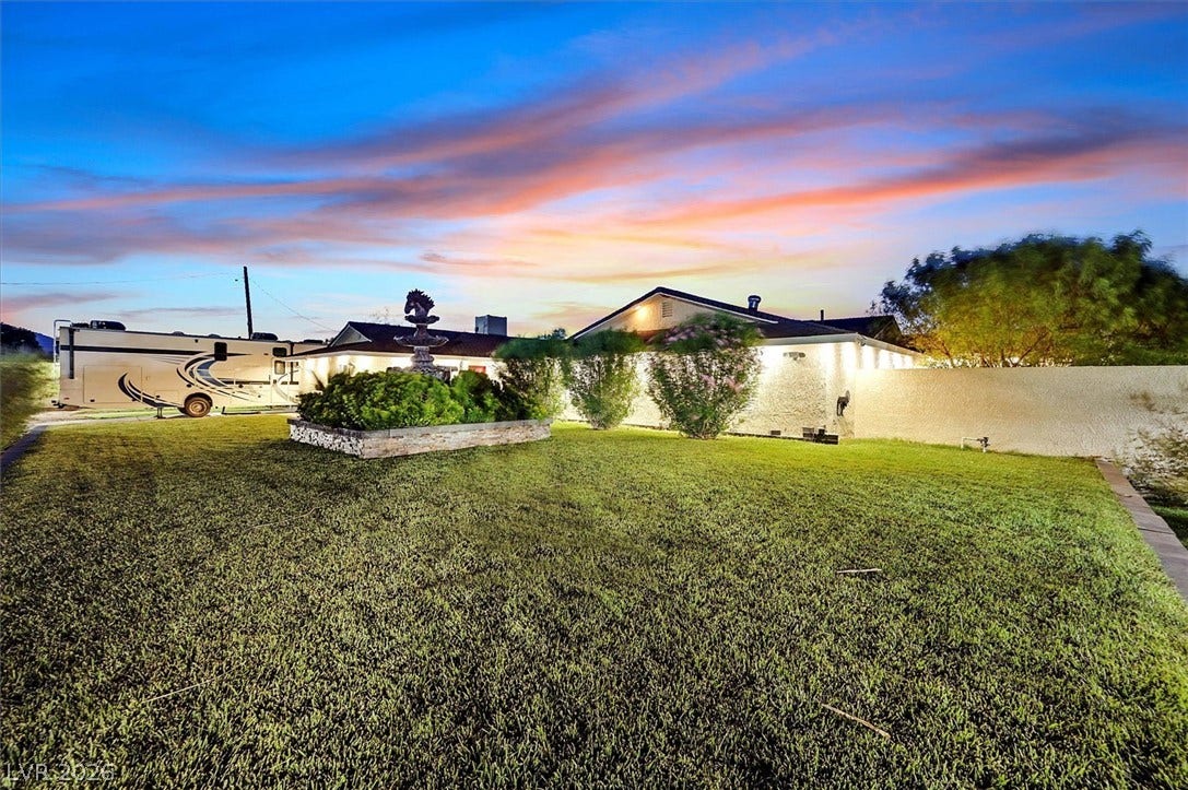 Well-maintained landscaping and privacy walls frame this residence beneath a vibrant sunset.